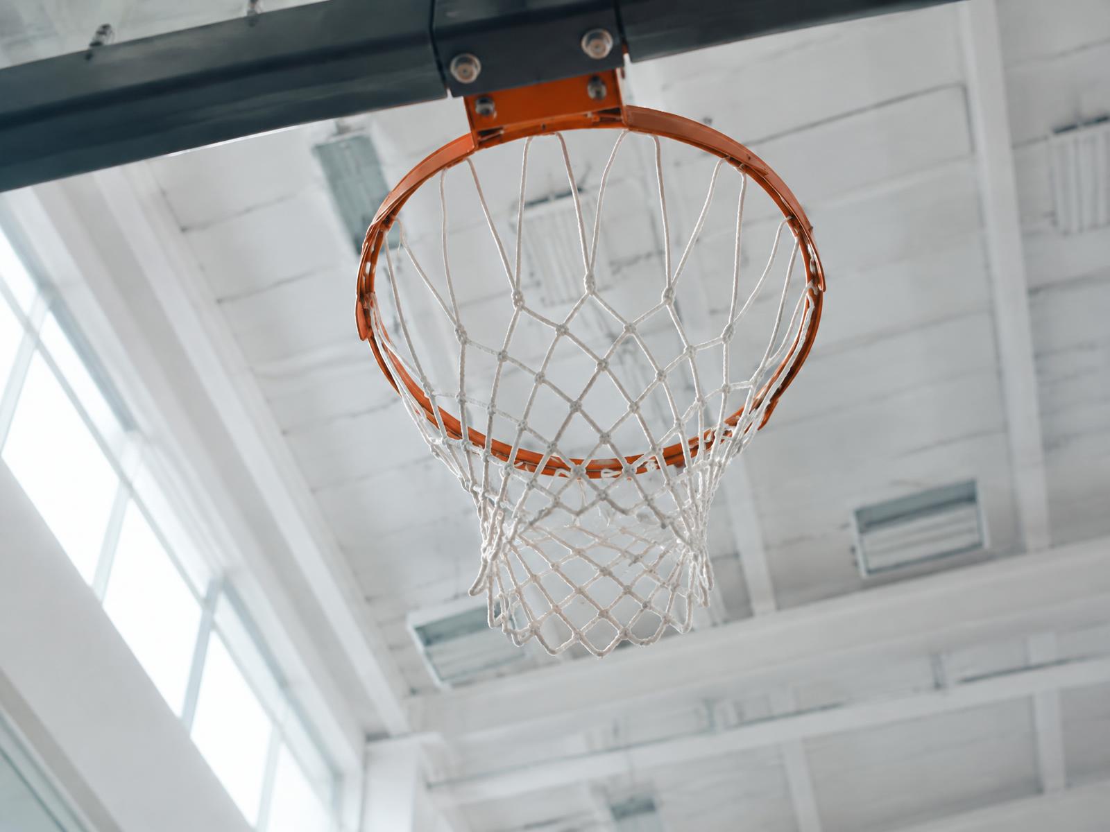Generated illustrative scene of a basketball hoop and backboard in a bright gym. Not a photo of a Rhino venue.